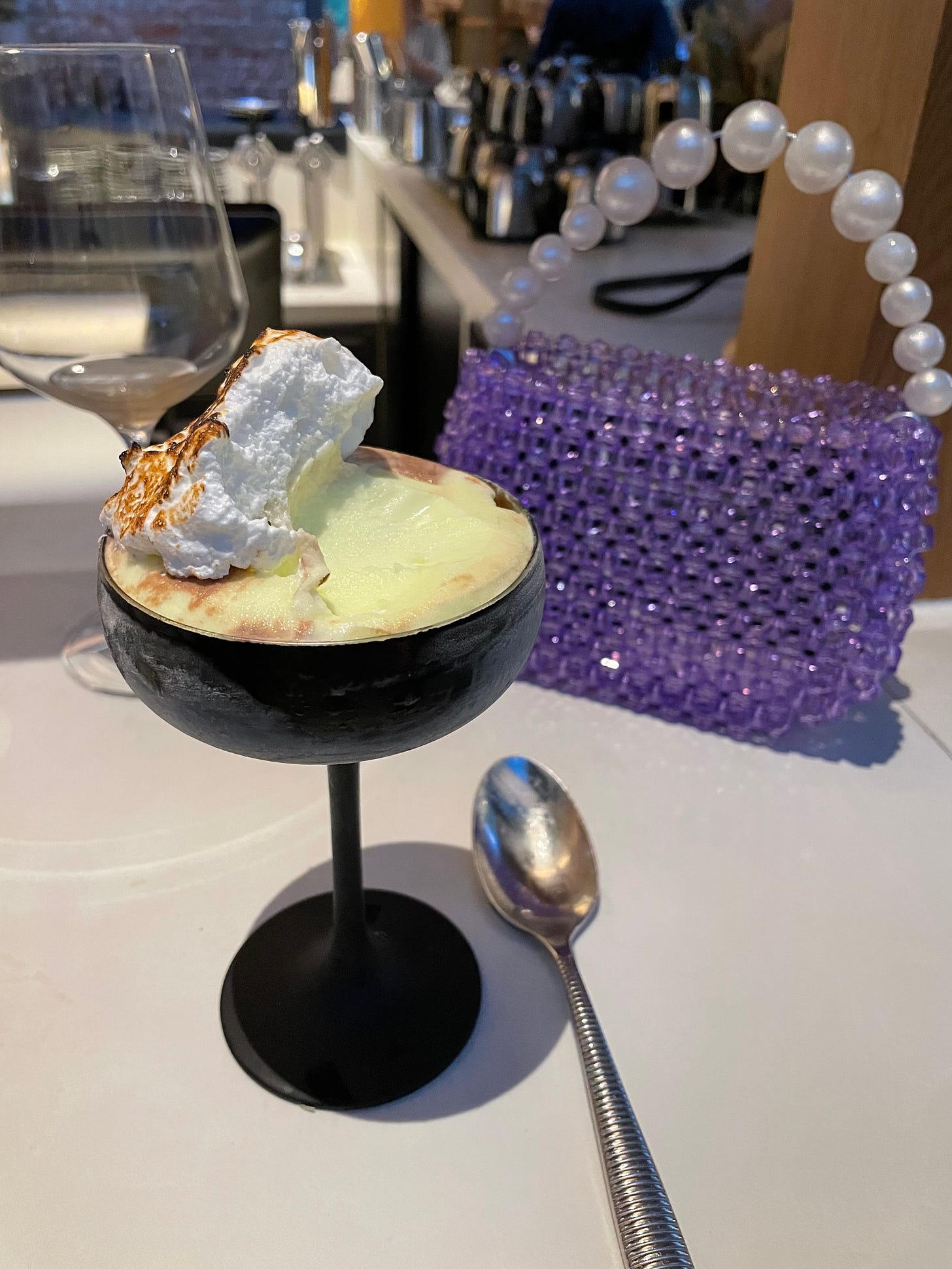 Lime sorbet in a couple with marshmallow on top, a purple handbag in the background