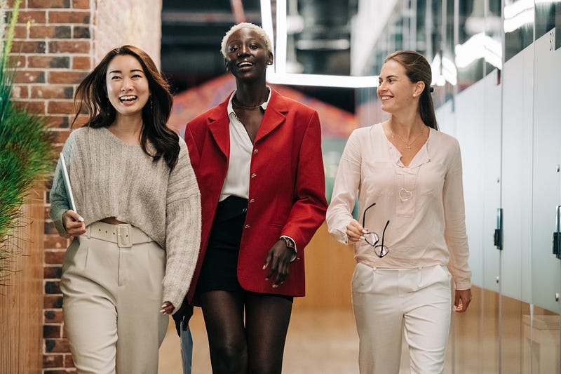 Três mulheres caminhando felizes num ambiente corporativo