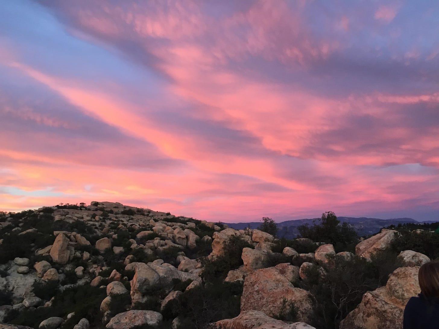 Photo of a pink and blue sky during sunset in Santa Barbara. The bottom half of the photo shows rocks.
