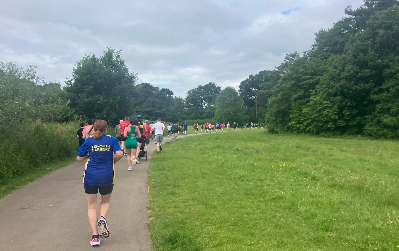 A long line of runners on a gently curving path