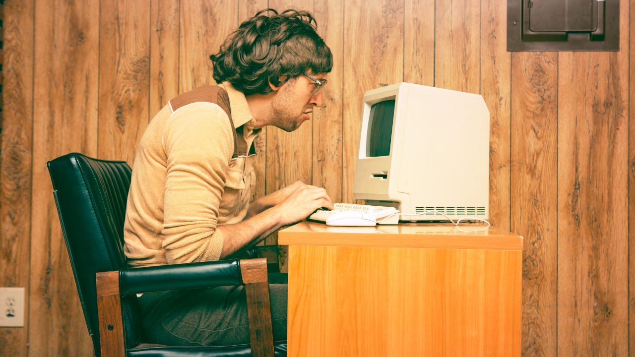 A man working on a old desktop computer. 