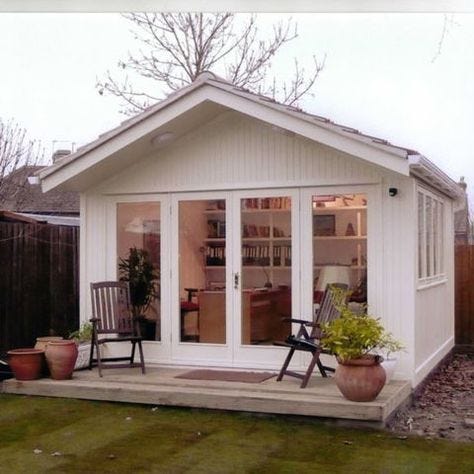 This may contain: a small white shed sitting on top of a grass covered yard