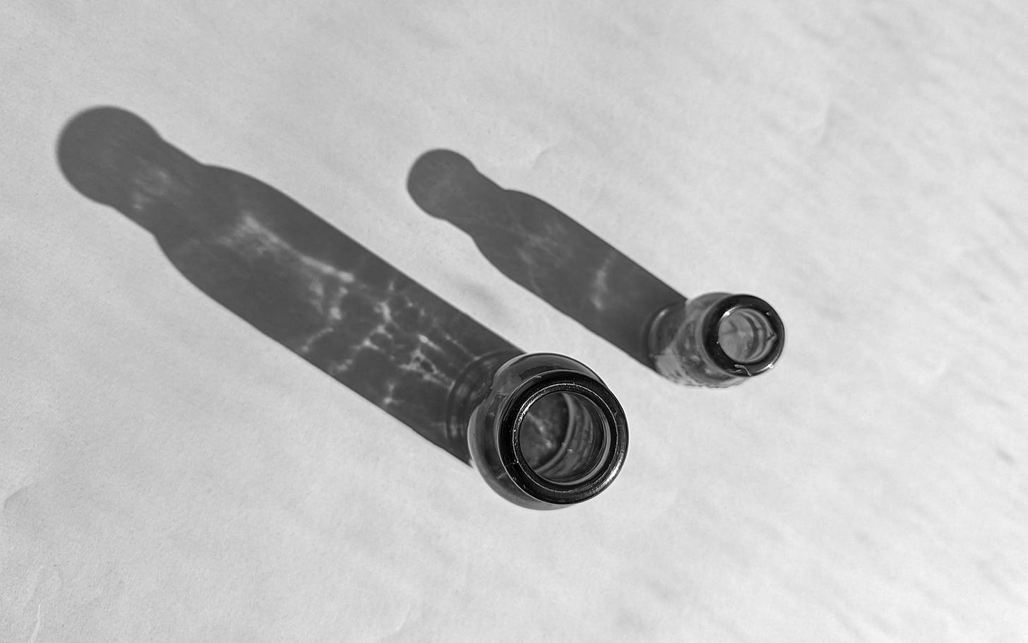 Two identical glass bottles cast shadows into the upper left hand corner of the ether.