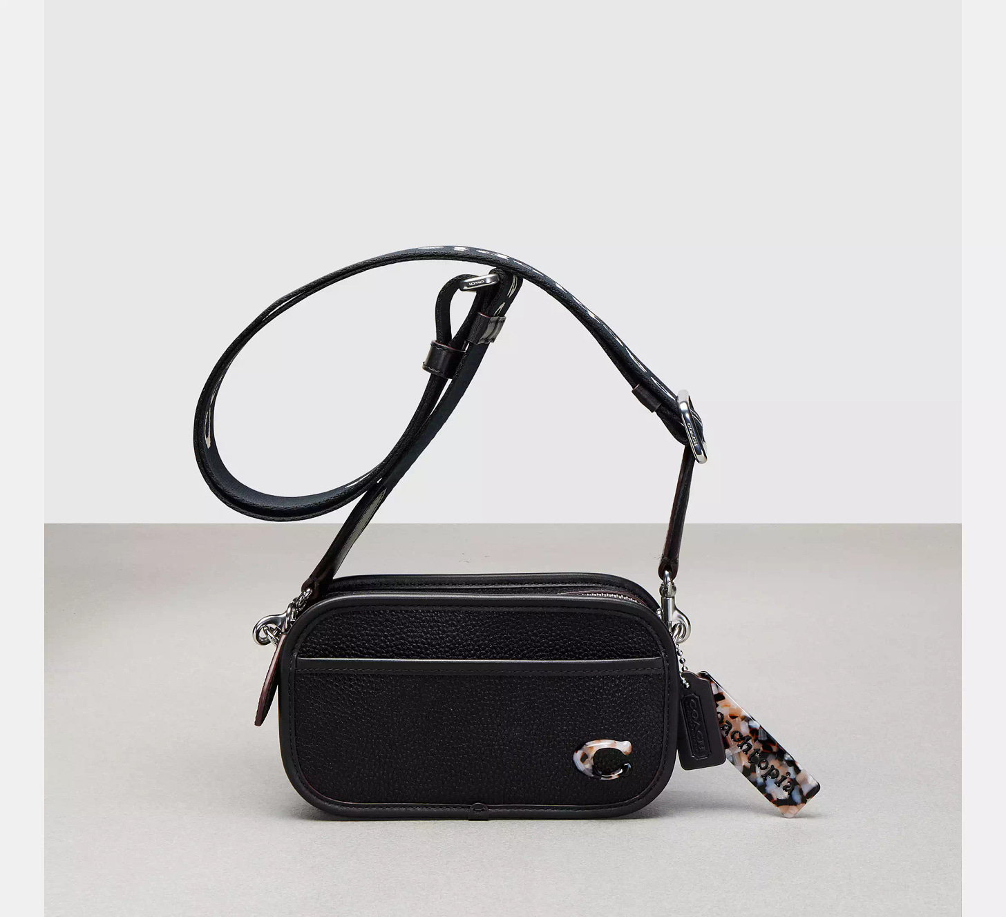 A black peddled leather Coach crossbody bag with a C logo on the front.