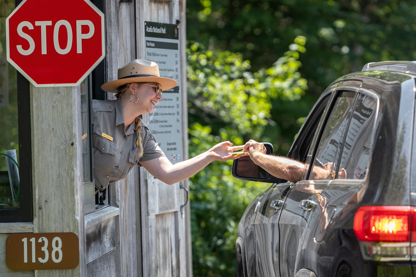 Acadia transitions to cashless fee collection A park ranger gleefully hands a park visitor a park pass.