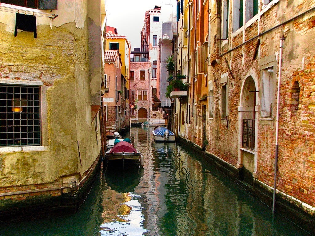 A canal between buildings with boats

AI-generated content may be incorrect.