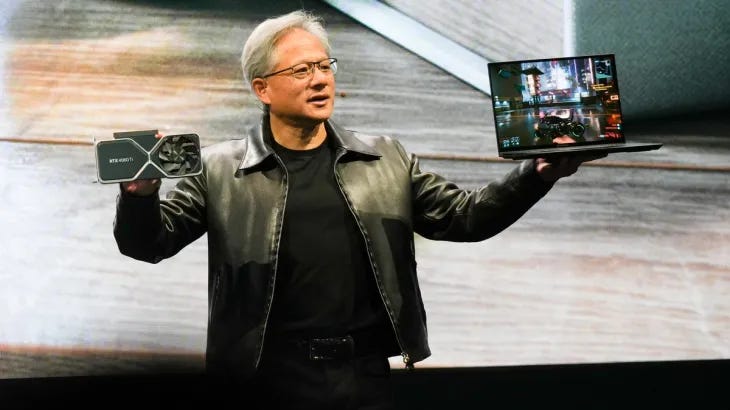 Nvidia CEO Jensen Huang showing off a GPU and a laptop on stage.