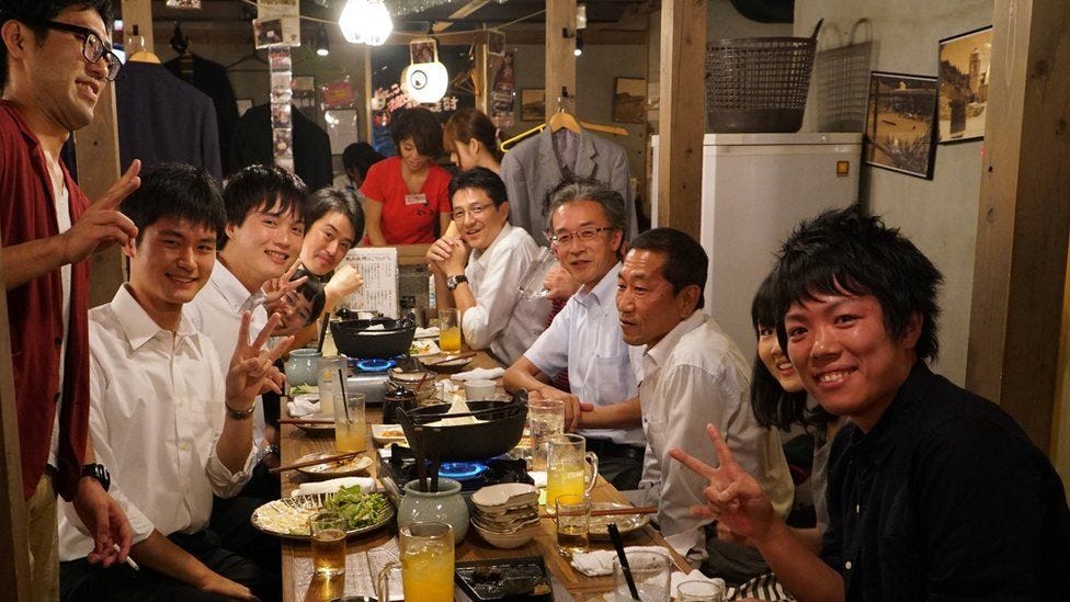 Men sit at a table at an after-work drinking party in Japan