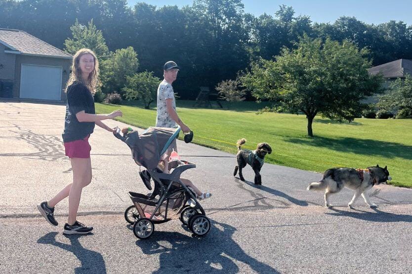 I walk up a street pushing my niece in a stroller and holding my parents' husky's leash. Sean walks next to us holding my mom's doodle's leash