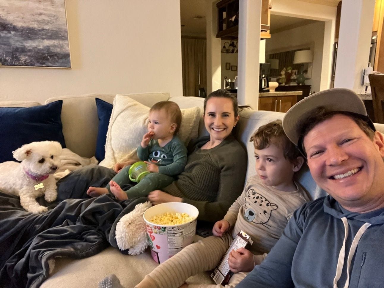 A family and dog sitting together on the couch eating popcon A family and dog sitting together on the couch eating popcon