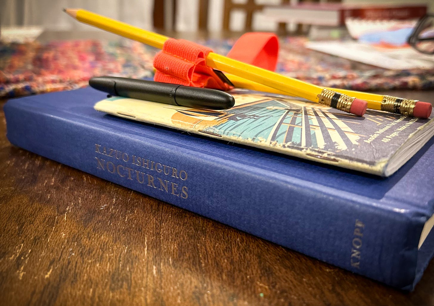 Book, Kazuo Isghiguro's Nocturnes, with pencils, pen, and notebook.