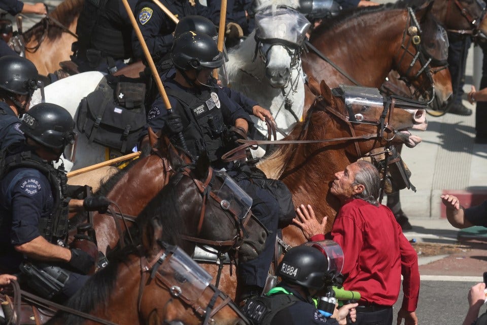 Demonstrator being blocked by mounted police officers during a protest.