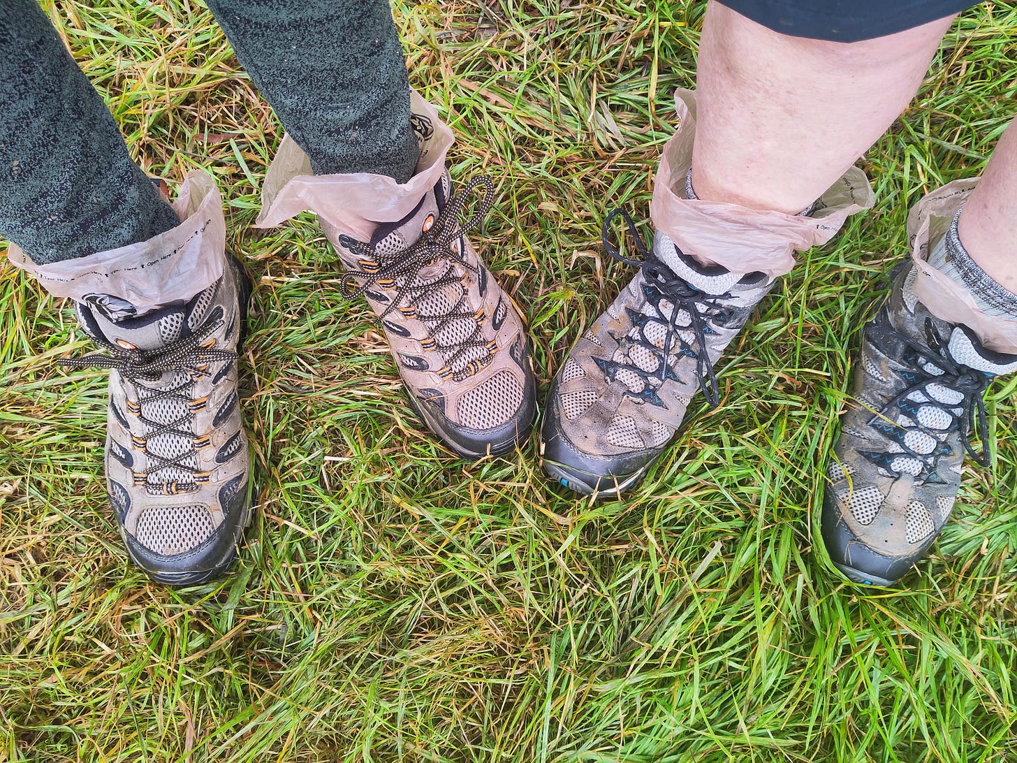 2 people's feet in boots on muddy ground 