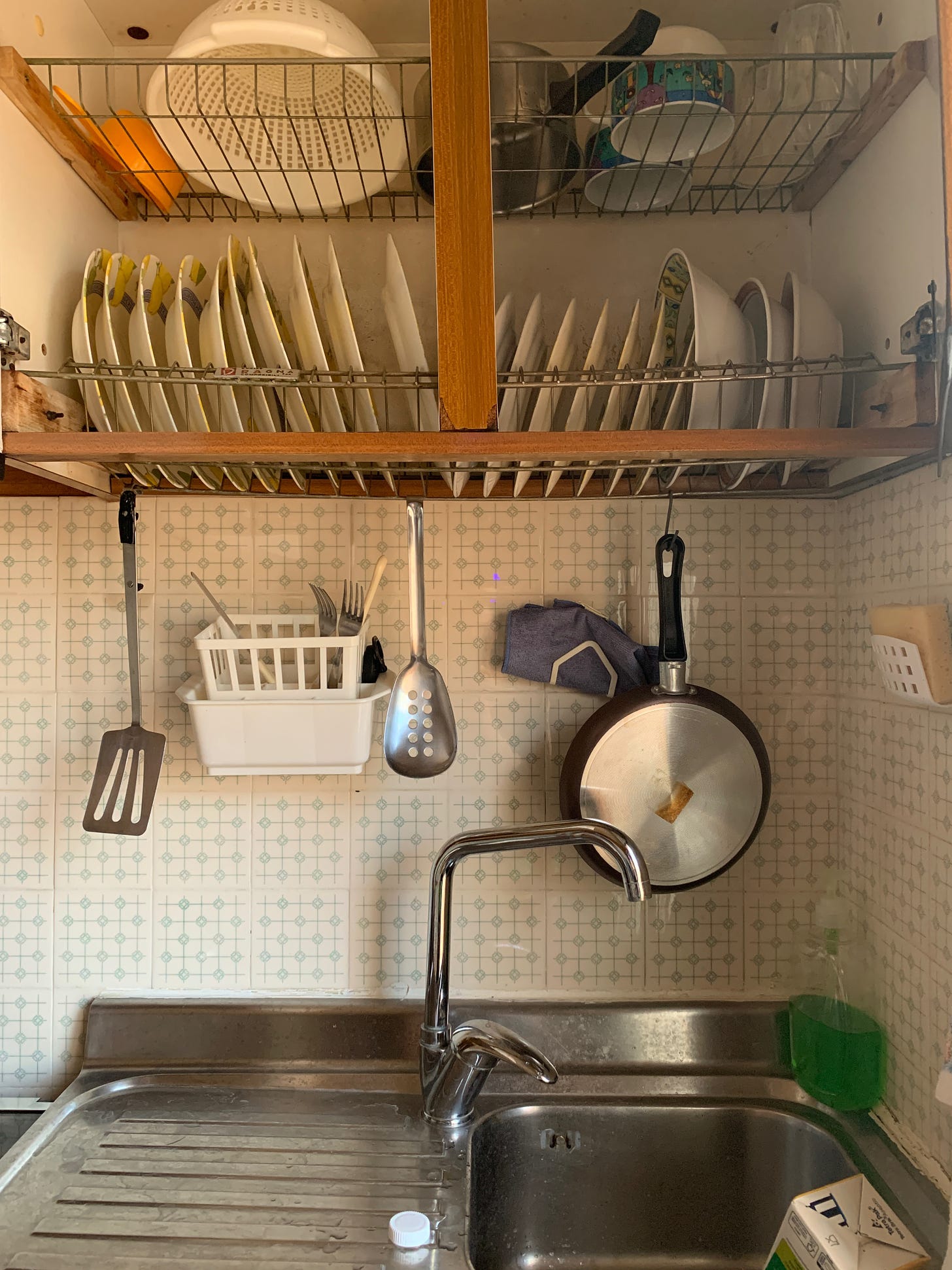 Sicilian kitchen cupboard with the dishes drying in place on racks above the sink. 