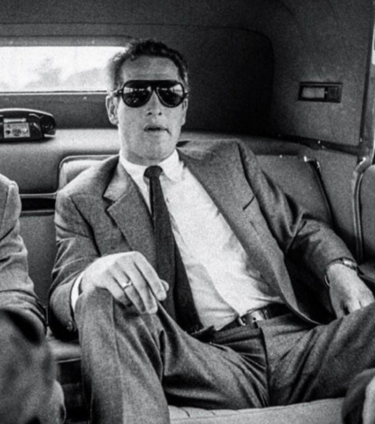 This may contain: two men sitting in the back of a car wearing suits and ties, one with sunglasses on