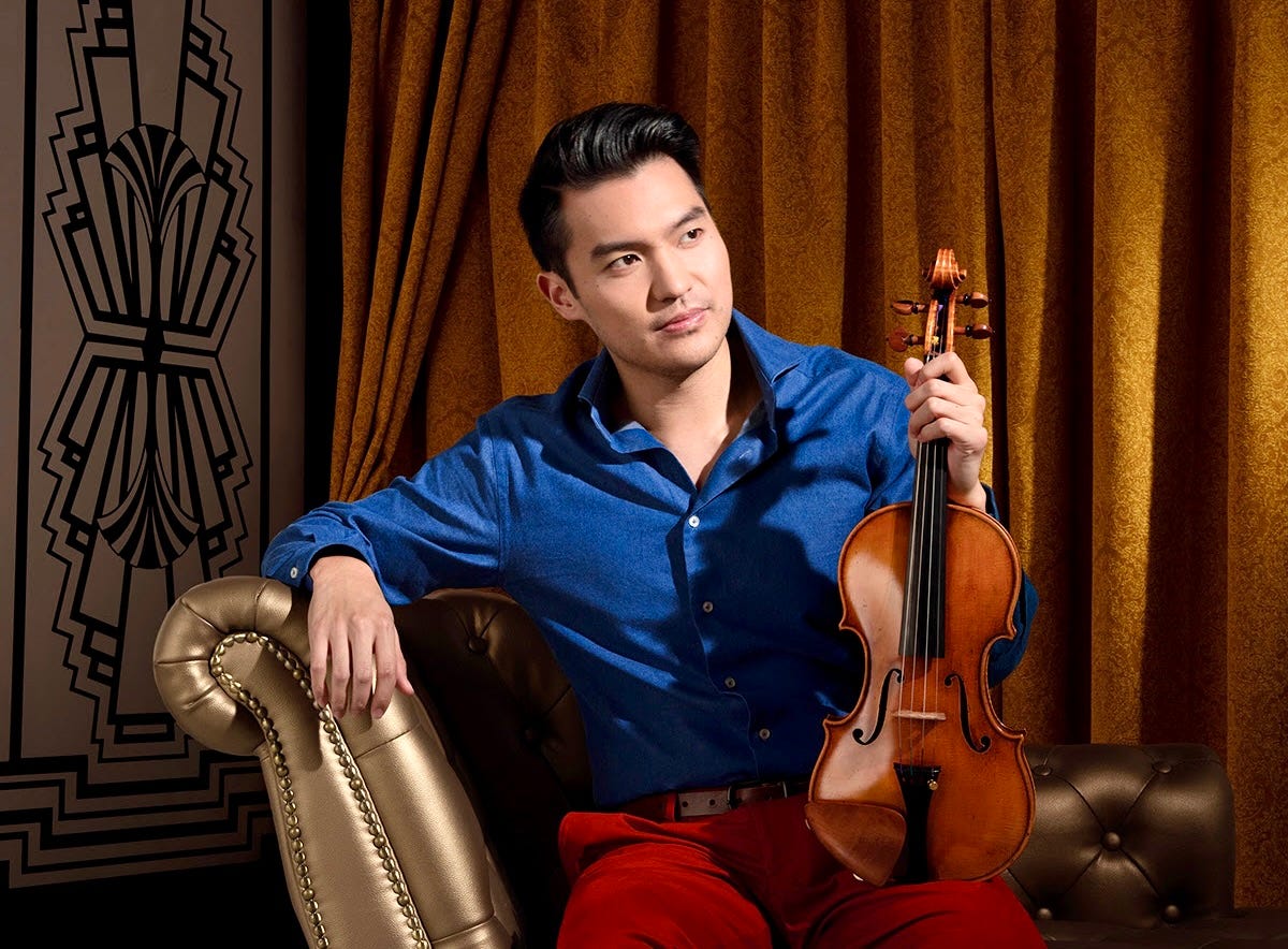A violinist poses on a chaise lounge