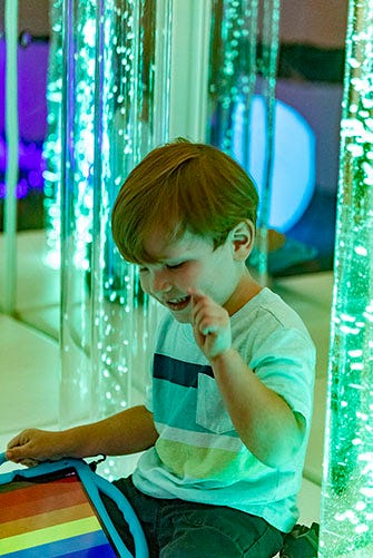 A young child chooses the color of bubble tubes.