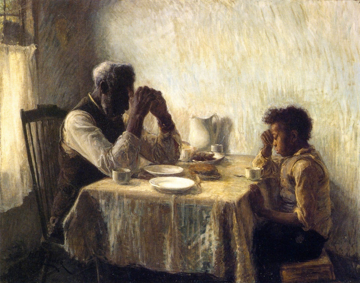 Two African Americans, an old man and a boy, facing each other and praying at a table over a modest meal