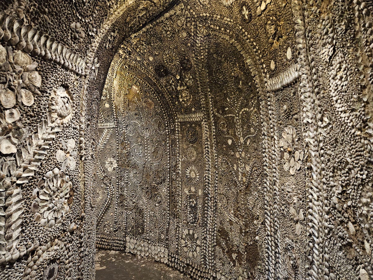 A curved passageway covered in shells