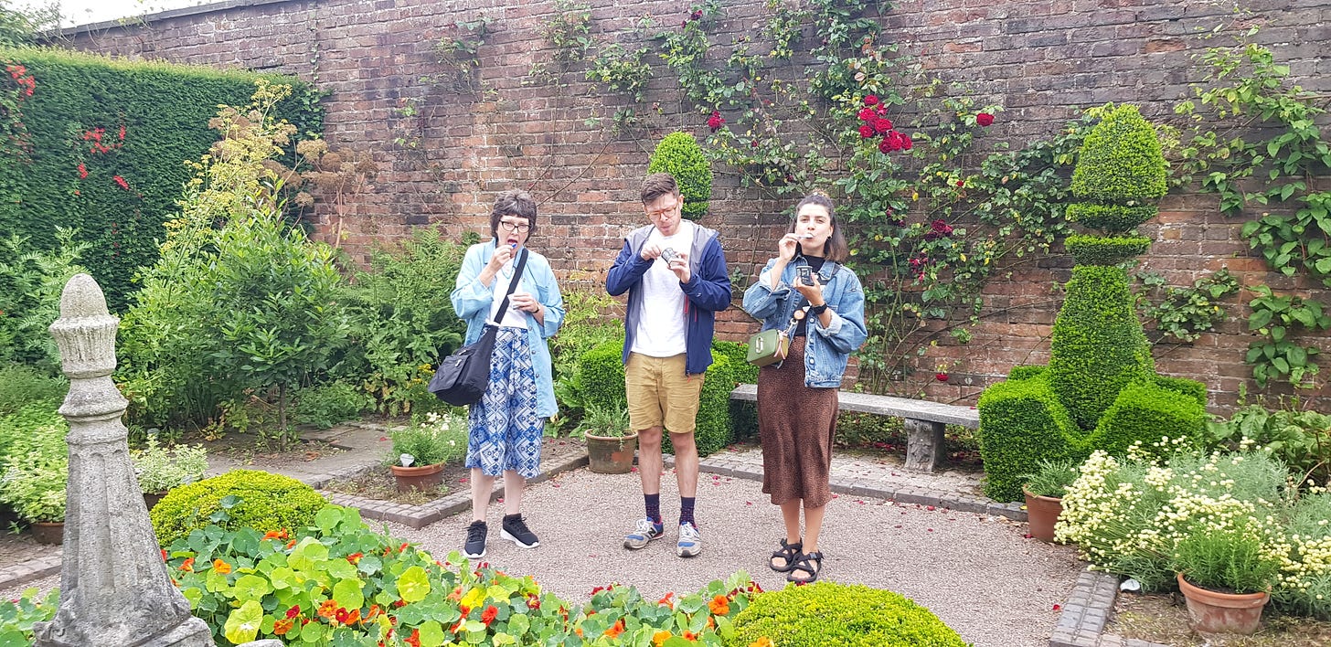 Three adults standing in a beautiful garden eating ice creams