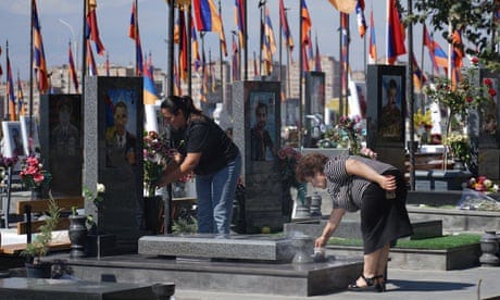 women laying flowers and lighting incense at a graveside