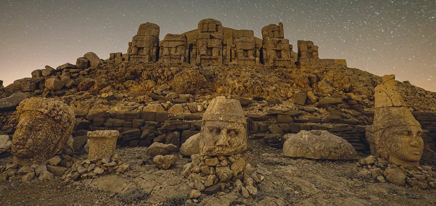 This nighttime photo shows three carved statue heads that have tumbled from their bases. They sit under a starry sky in front of Mount Nemrut, in Turkey.