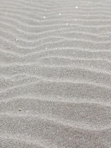 rippled dark sand with sparkles of shimmery material