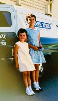 A couple of children standing next to a van

Description automatically generated