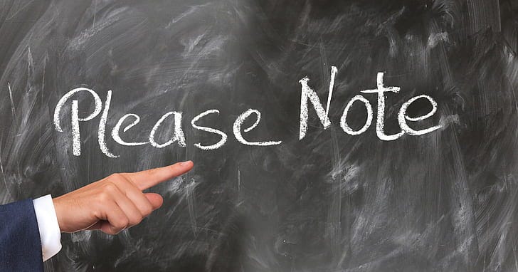 A hand pointing at a blackboard with "Please Note" written on it in white chalk