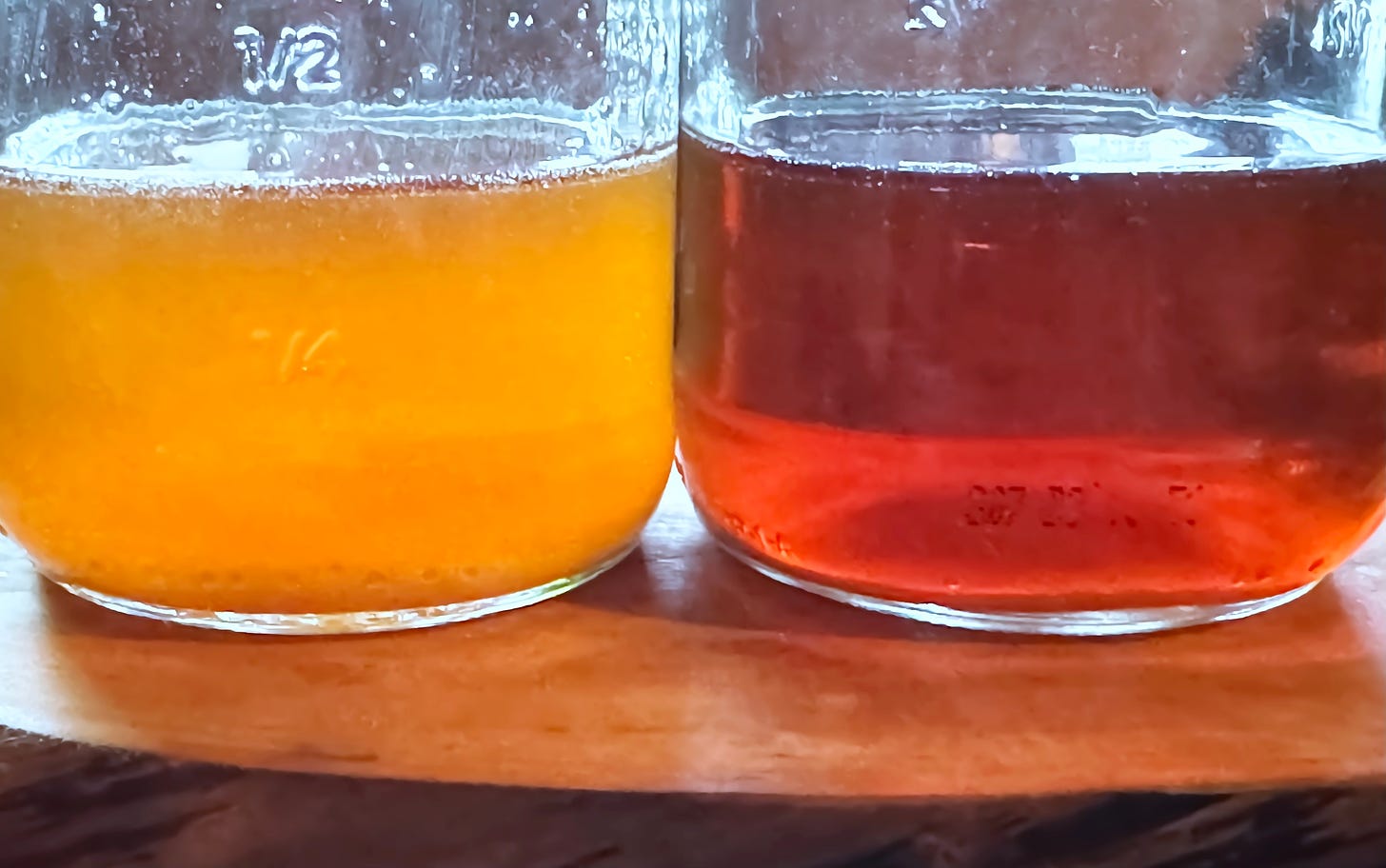 Two jars of maple syrup, golden on the left, amber on the right.