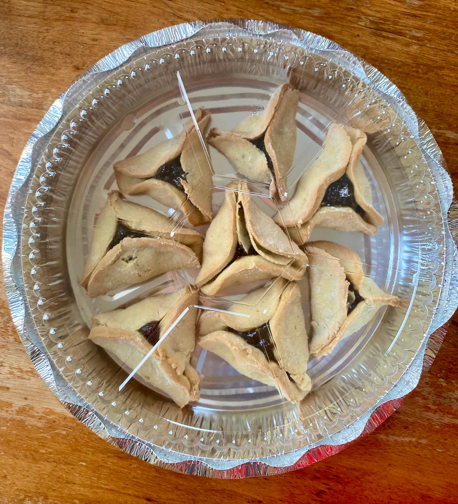 A metal takeout tray filled with hamantaschen