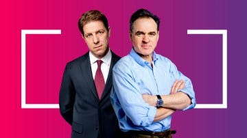 Two men standing side-by-side. One in a suit, the other in a shirt.