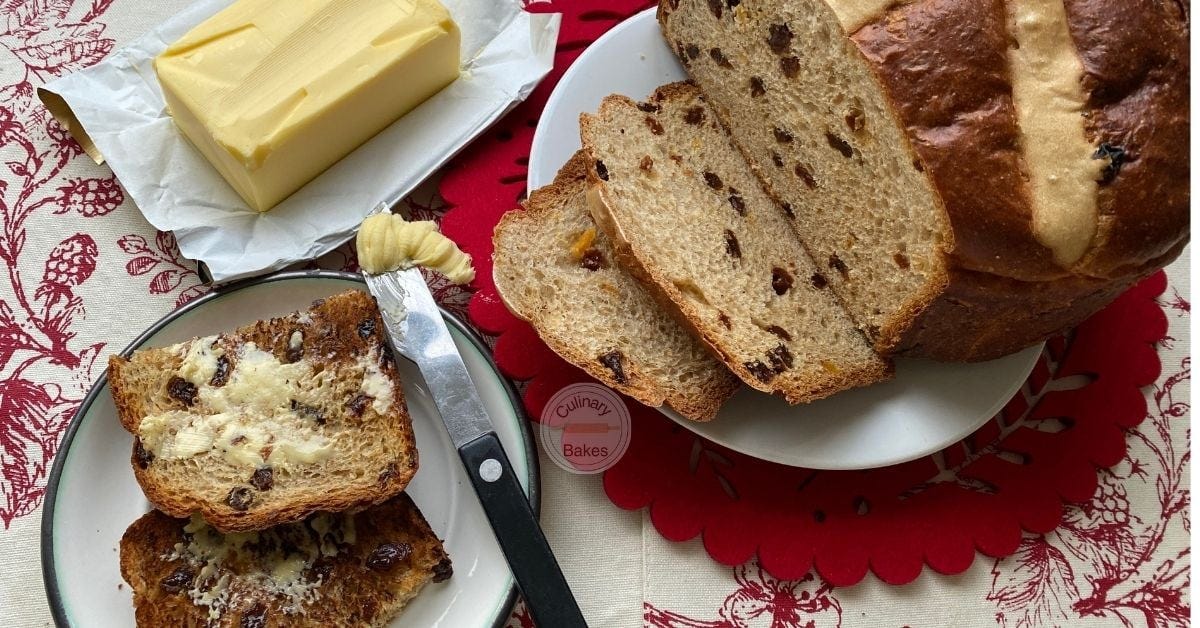 Large Hot Cross Bun Sliced with a dish of butter on the side.