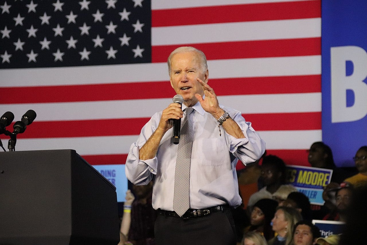 President Joe Biden speaking at a rally in front of a large American flag