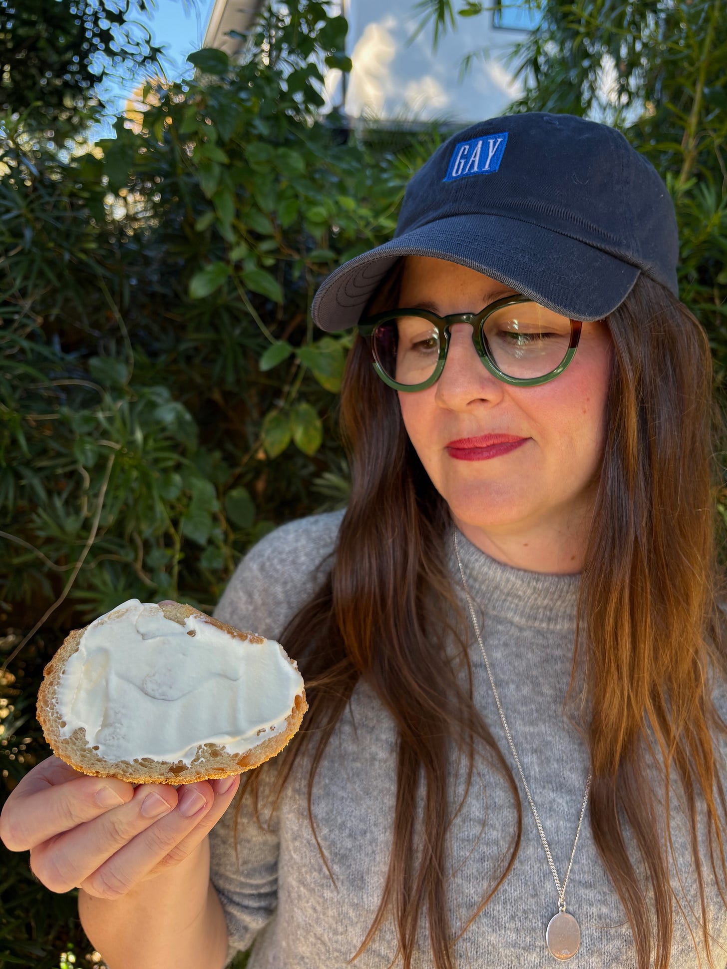 kristen in gay hat looking at her buttered bread outside