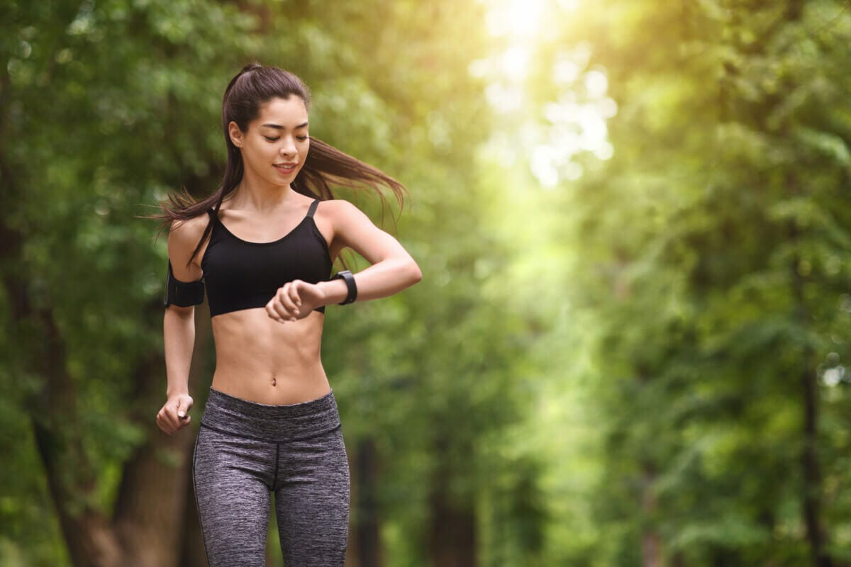 Young woman jogging and looking at smart wristwatch