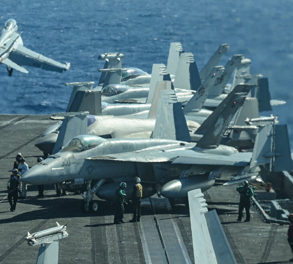 Fighter jets on the deck of an aircraft carrier.