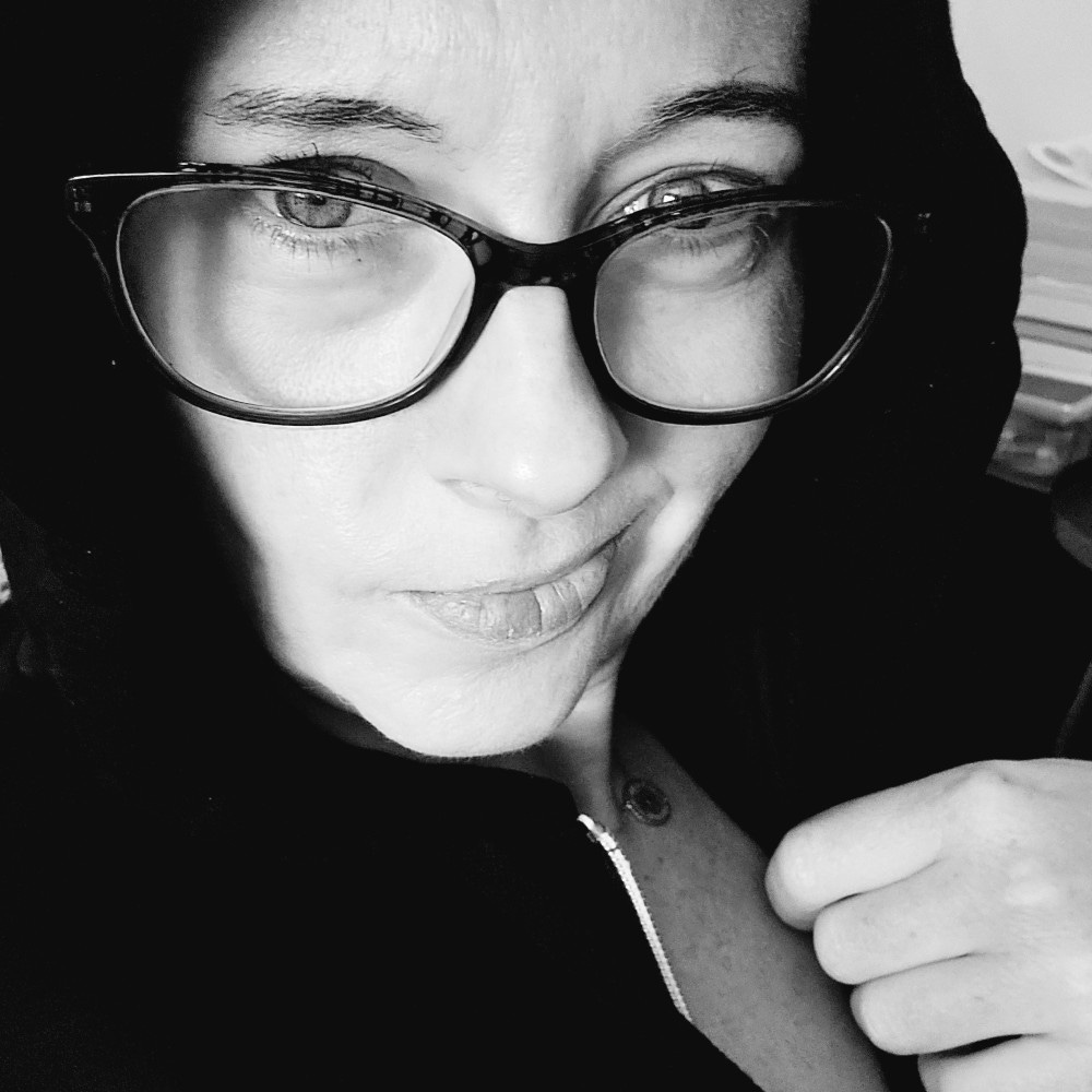 A woman wearing a hoodie with glasses on in a black and white photo