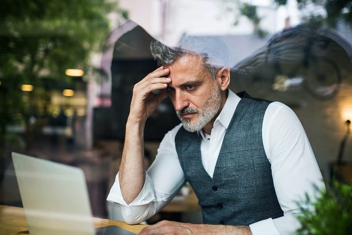 An older gentleman looking depressed in front of a laptop. An older gentleman looking depressed in front of a laptop.