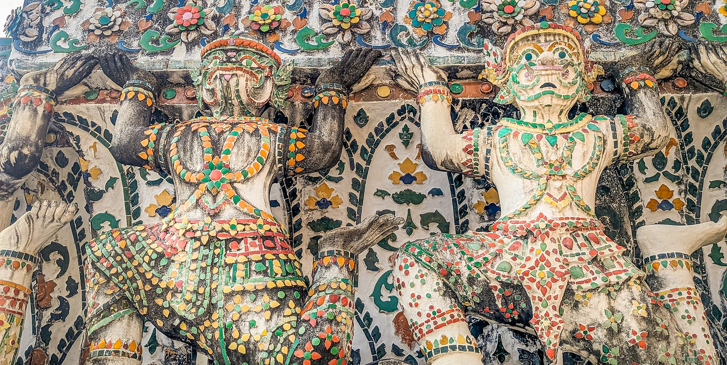 A closeup of two Yaksha decorated with colorful bits of porcelain.