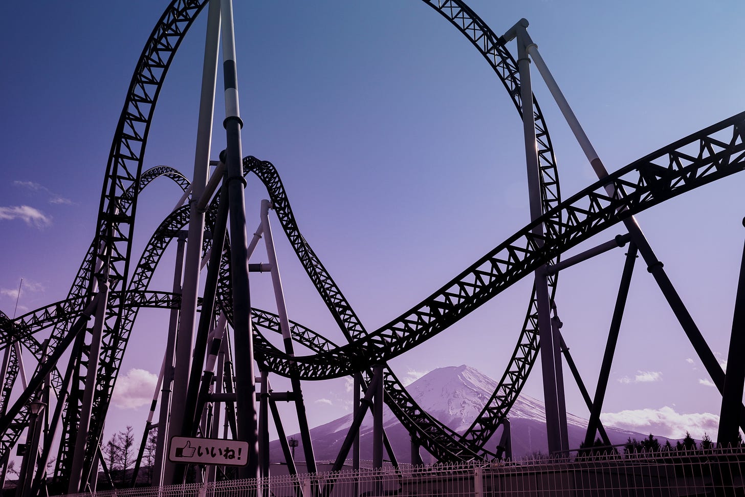 Large roller coaster track against a blue and purple sky with mountains in the distance.
