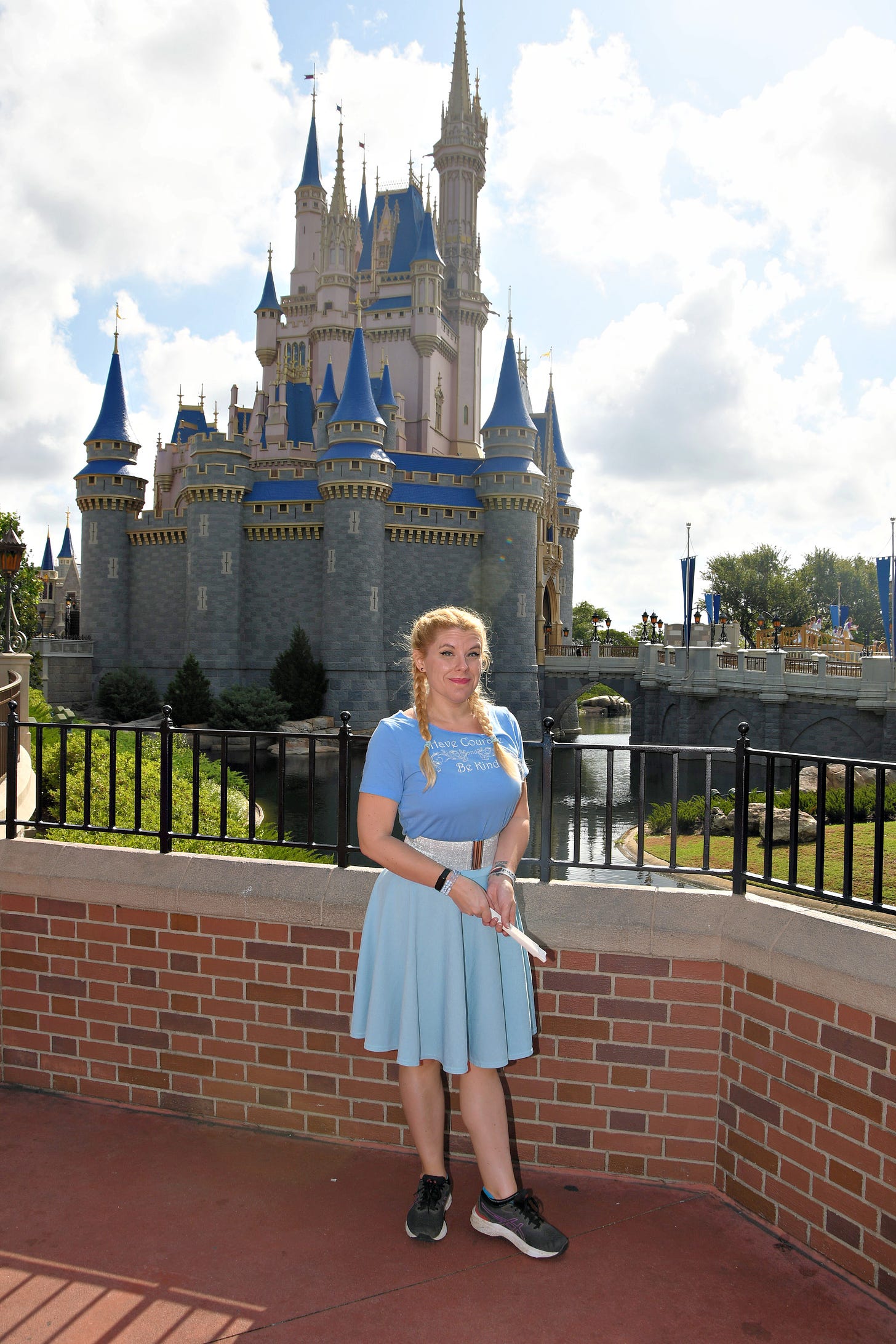 Cass standing in front of Cinderella's Castle in the Magic Kingdom on a partly cloudy day