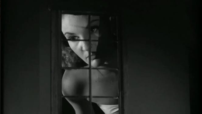 Movie still from Attack of the 50 Foot Woman. A huge woman peers through a house window from the outside.