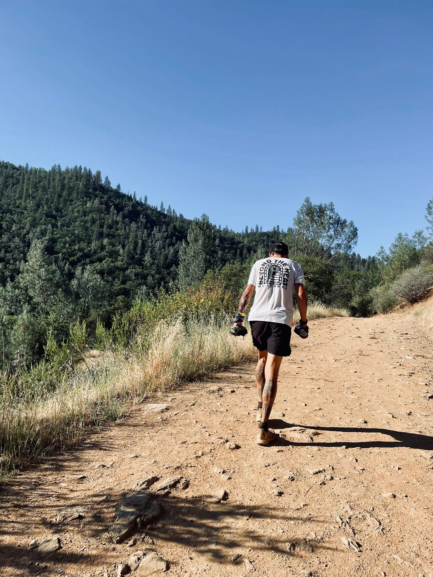 the author hiking up a dusty trail with 2 hand bottles at the western states endurance run 2022