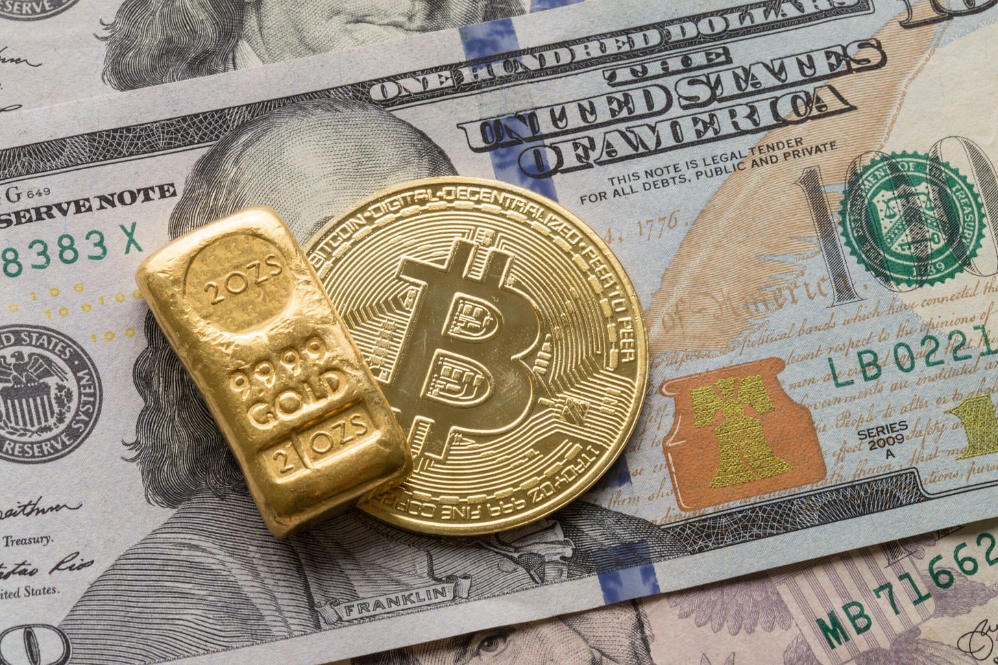 Gold Bullion and Bitcoin Cryptocurrency on 100 US Dollar (Shutterstock)