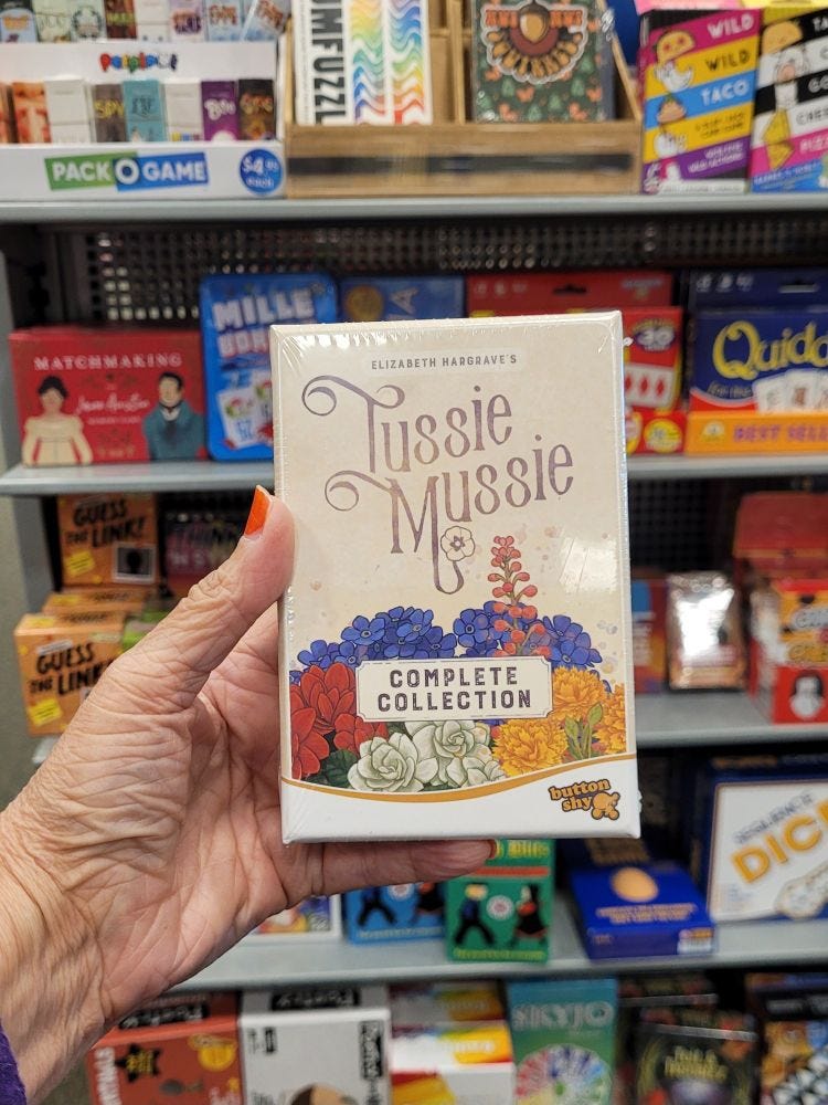 Holding up the small box of Tussie Mussie Complete Collection. It'll almost fit in my hand! In a Barnes and Noble store. Backdrop is a rack of very small box games. Holding up the small box of Tussie Mussie Complete Collection. It'll almost fit in my hand! In a Barnes and Noble store. Backdrop is a rack of very small box games.