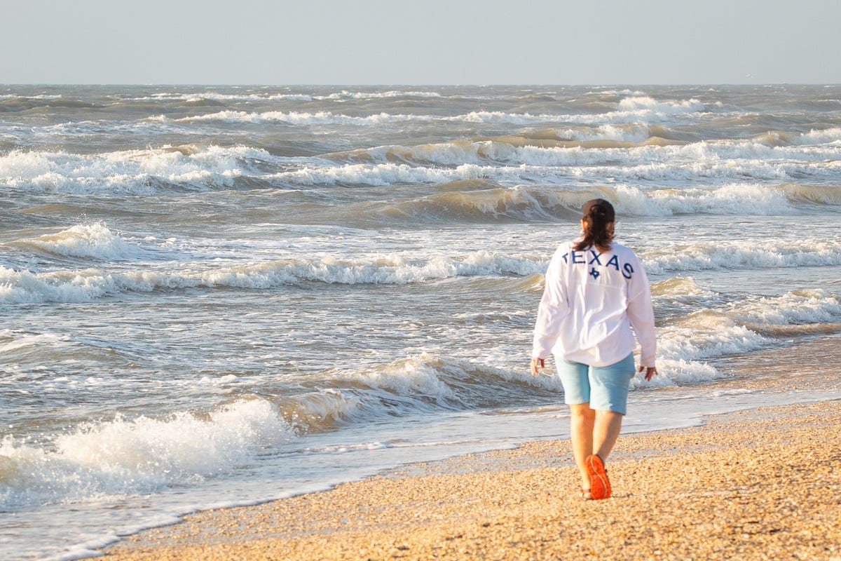 Walker on beach, watching waves on sea