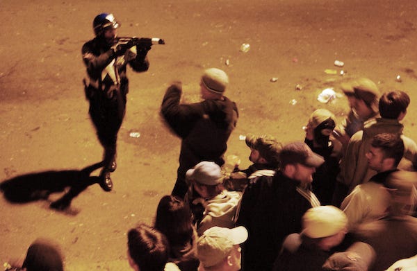 A Boston police officer aims an FN303 pepper ball gun at the crowd outside Fenway Park.