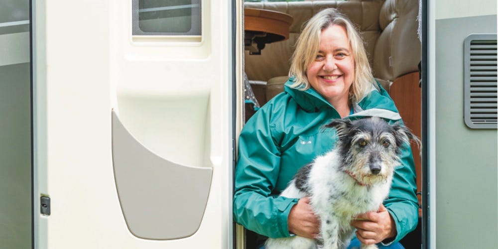 Photo of Jo Scott and her dog Thomasina sat in the open doorway of a motorhome