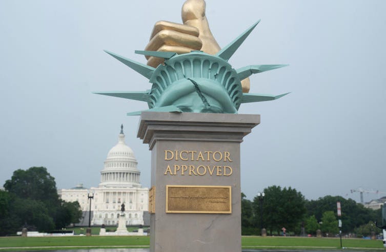 Temporary art on the National Mall on a base saying Distator Approved with a thumbs up smashing the head of the statue of liberty Temporary art on the National Mall on a base saying Distator Approved with a thumbs up smashing the head of the statue of liberty